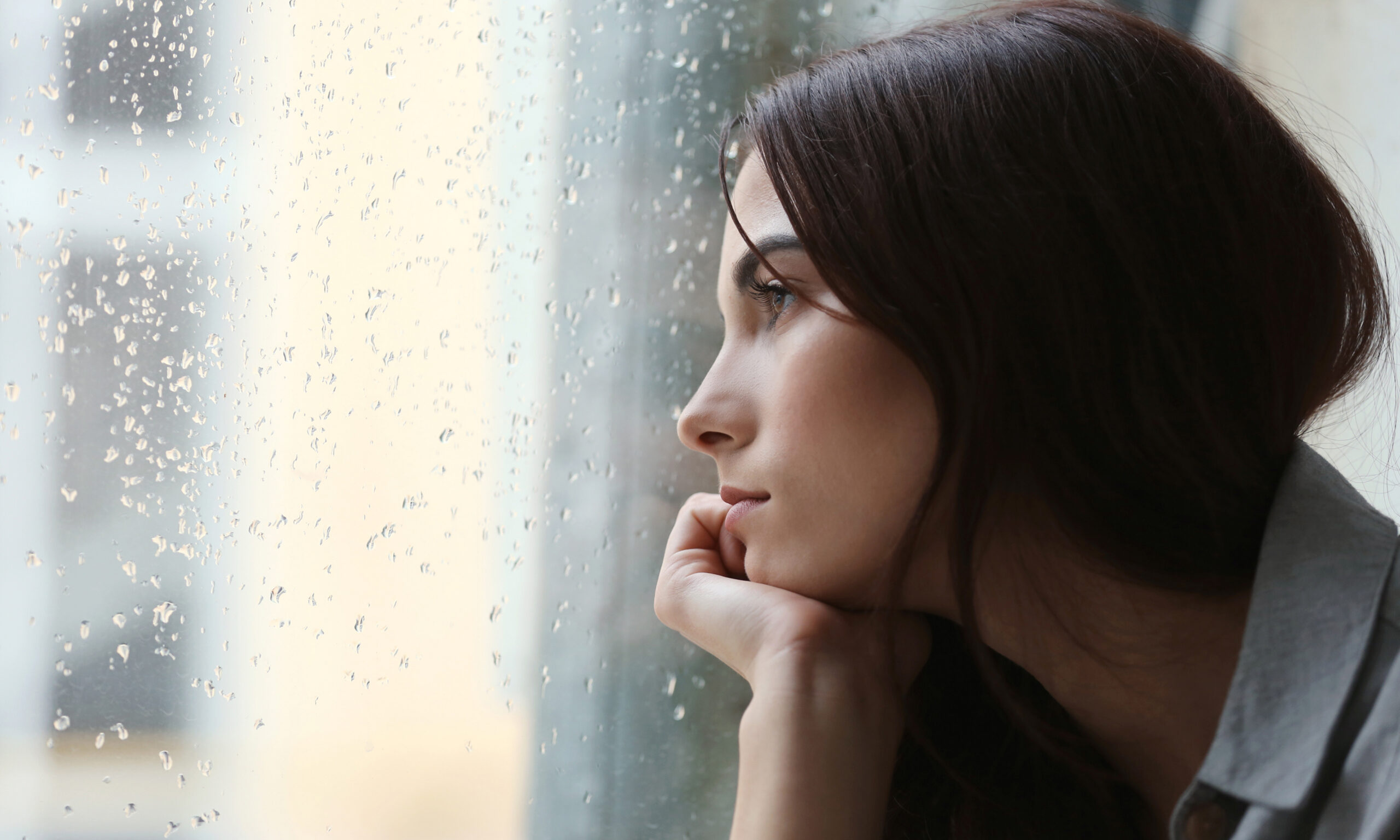 depressed woman looking out the window